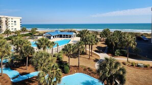 Un complexe hôtelier doté d’une piscine, de palmiers et offrant une vue sur l’océan.
