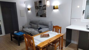 Ein gemütlicher Wohnbereich mit Essbereich, einer Couch, einem kleinen Tisch und einer Küchenzeile.