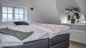 Een slaapkamer met een bed, een raam en een bloempot op een vensterbank.