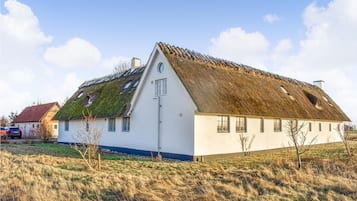 A white house with a thatched roof and a small garden.