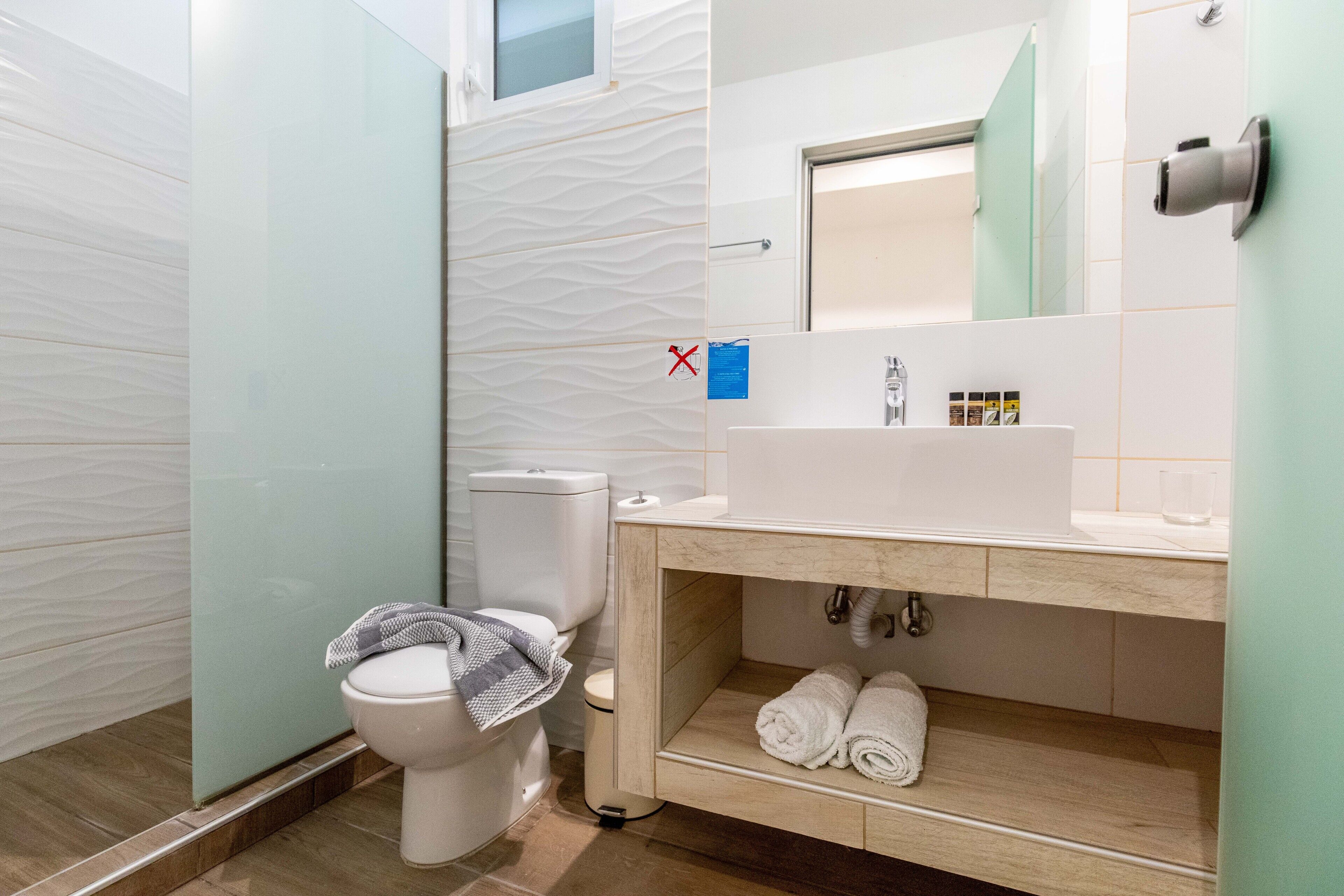 Un baño moderno con inodoro, lavamanos y toallero.