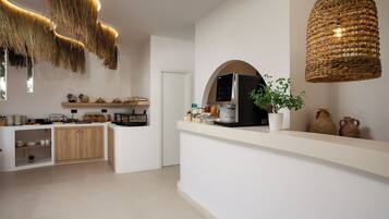 A modern kitchen with a white countertop, wooden cabinets, and a hanging light fixture.