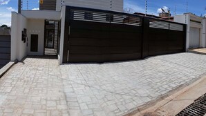 Una entrada con puerta metálica y un camino pavimentado que conduce a un edificio.