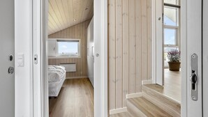 A narrow hallway with wooden walls and a sloped ceiling, leading to a bedroom with a window and a radiator. - Pet friendly home in Hejls with WiFi (Hejls)