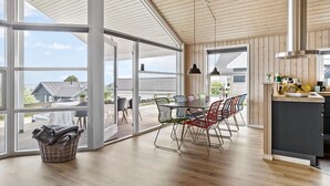 A spacious room with large windows, a dining area with colorful chairs, and a kitchen with wooden cabinets and a stainless steel range hood. - Pet friendly home in Hejls with WiFi (Hejls)