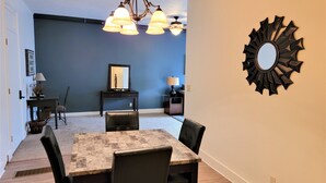 A dining area with a table and chairs, a chandelier, a mirror, and a blue accent wall.
