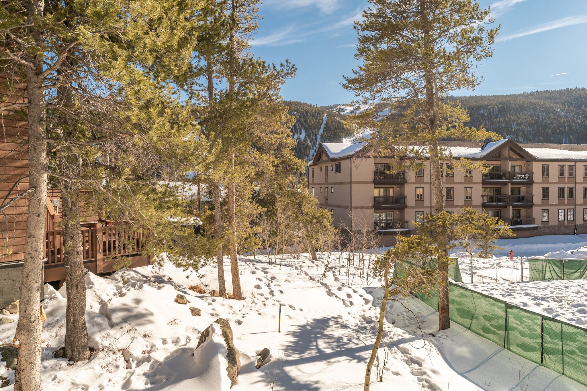 A hotel with multiple floors, a ski slope, and a mountainous backdrop.