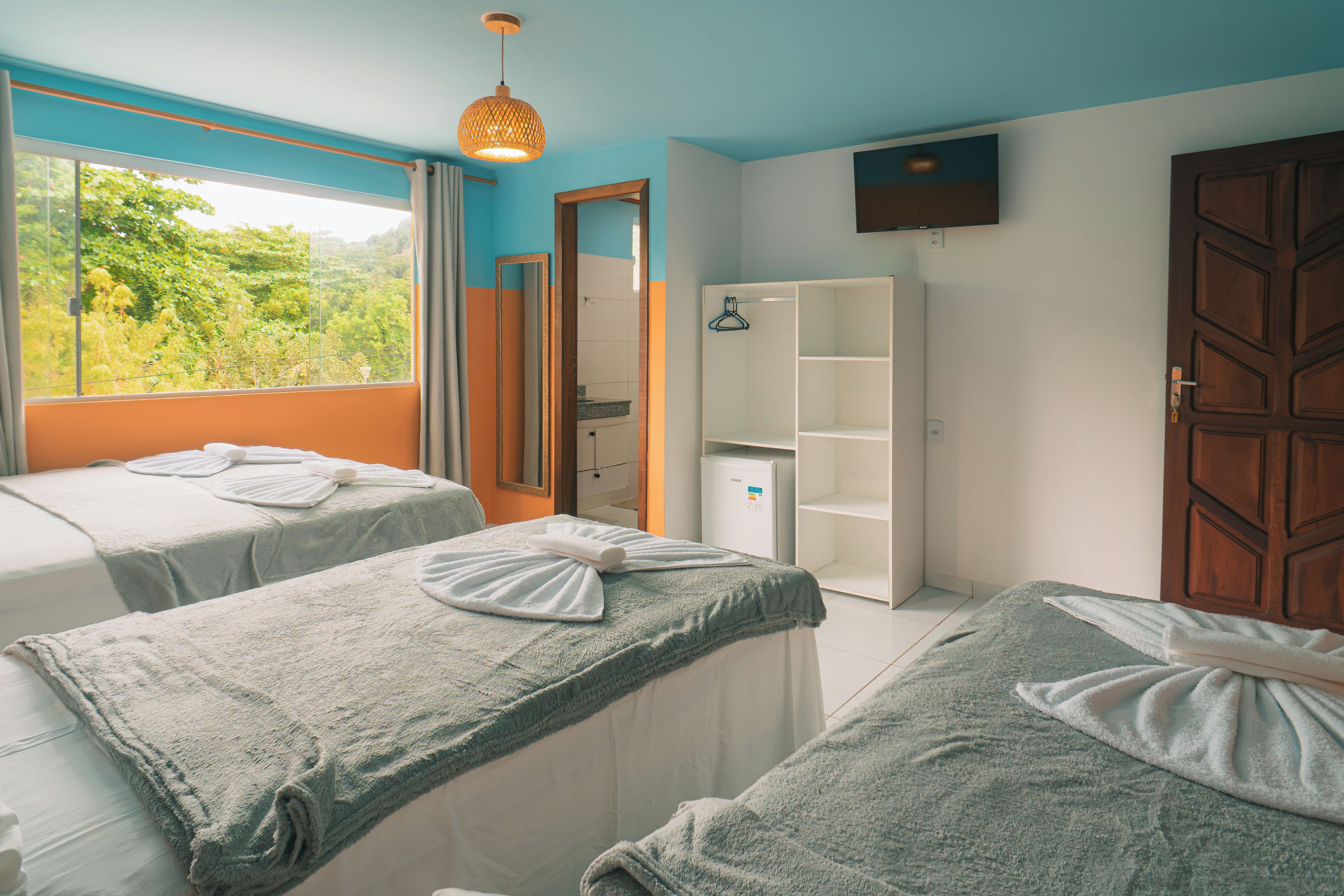 A room with two beds, a wardrobe, a mirror, and a television.