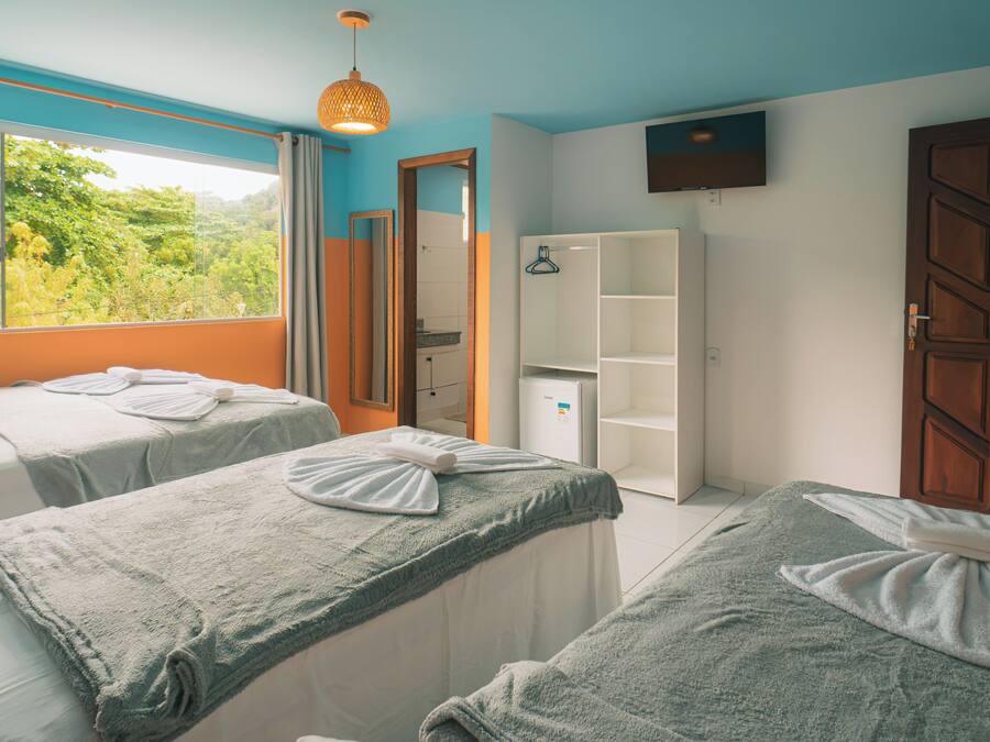 A room with two beds, a wardrobe, a mirror, and a television.