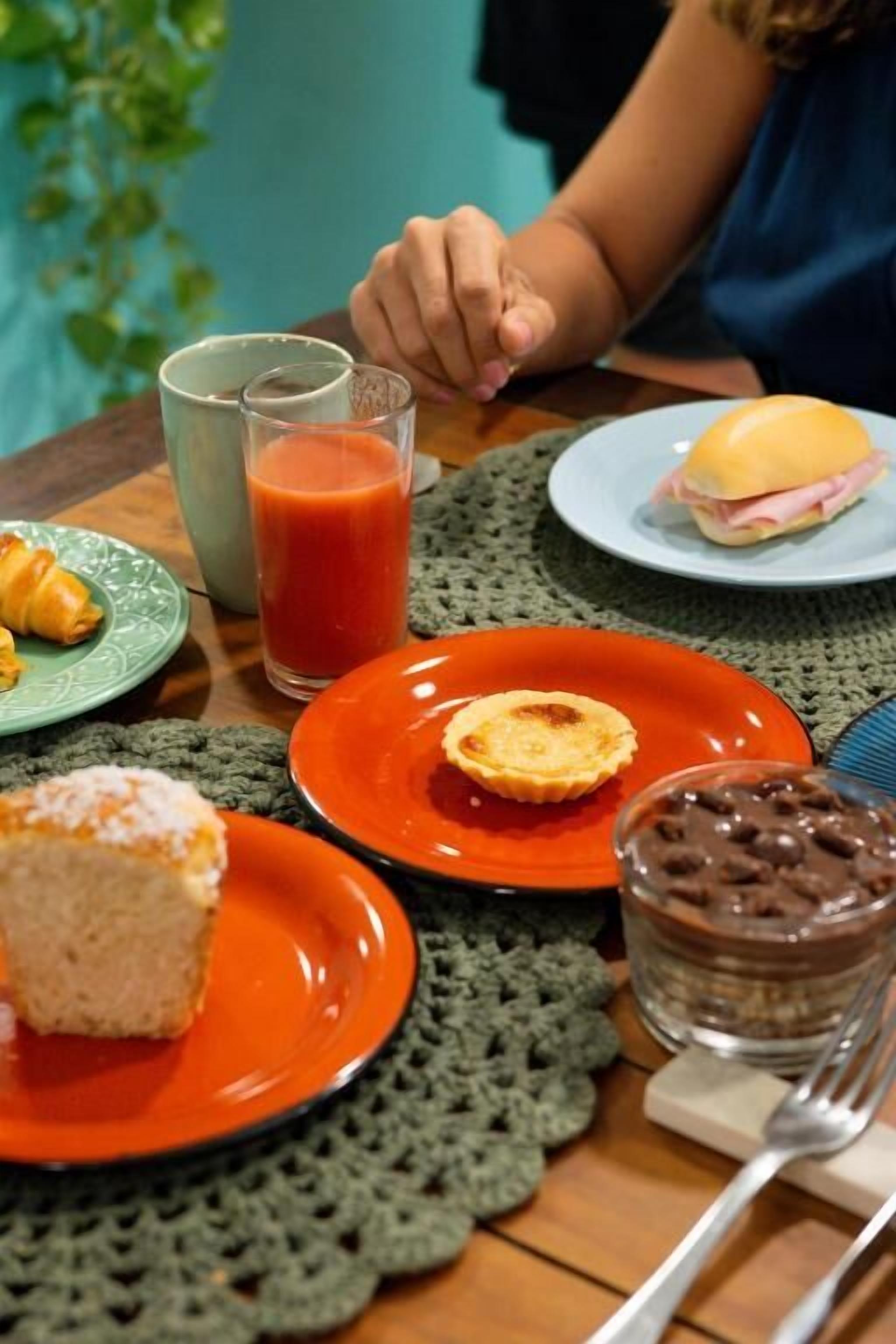 A table with a plate of food, a glass of juice, and a plate with a sandwich.
