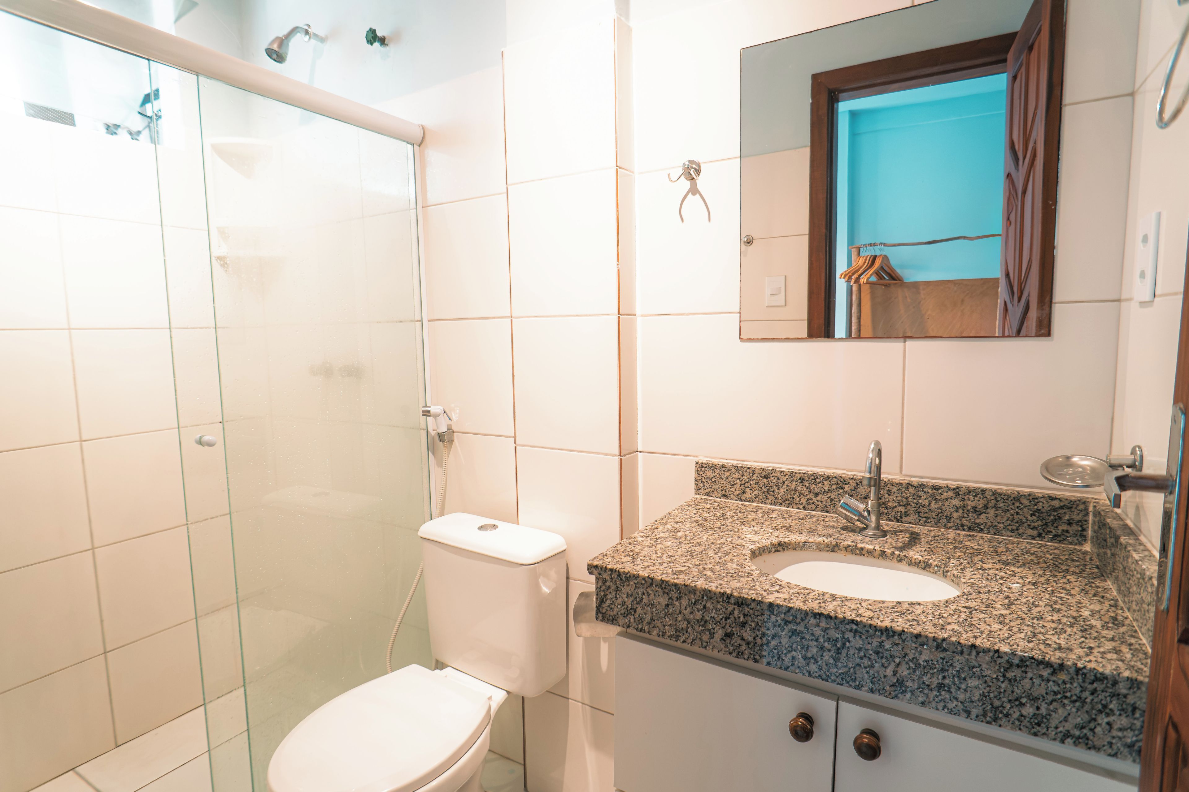 Un baño con ducha, inodoro, lavamanos y espejo.