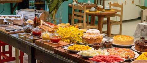 Una mesa de buffet con diferentes alimentos y un jarrón con flores amarillas.