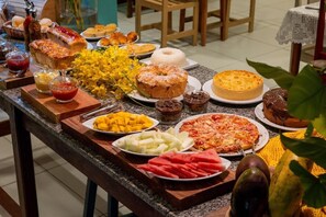 A buffet table with various food items including pastries, fruits, and desserts. - Hotel do Pescador (Cairu)