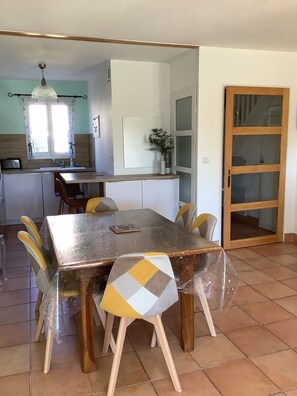 Un comedor con mesa y sillas, una cocina al fondo y un ventanal corredero.