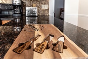 A wooden cutting board with four cheese graters on a granite countertop.