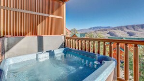 A hot tub on a balcony with a view of mountains.