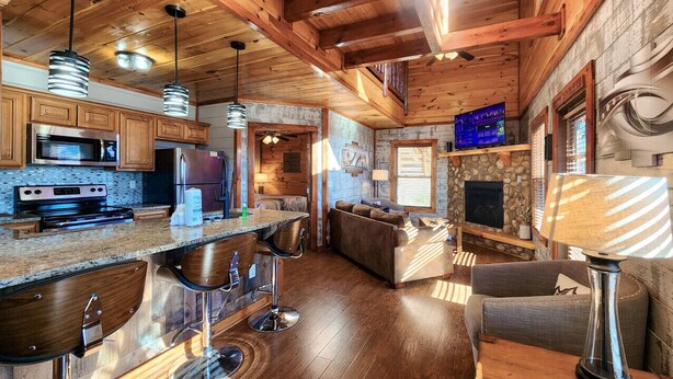 A spacious kitchen with wooden cabinets, a built-in microwave, and a large island with bar stools.