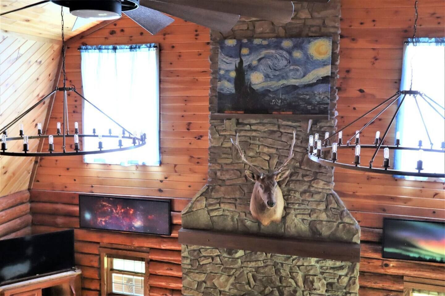 Ein Innenraum einer Blockhütte mit Kamin aus Stein, angebrachter Kunst und einem aufgehängten Hirschkopf.