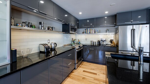 A modern kitchen with dark cabinets, stainless steel appliances, and a wooden floor. - Telemark Long Stay Condo: Perfect For 30 Days Or More (Breckenridge)
