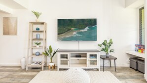 Una sala de estar moderna con un televisor de pantalla plana, una estantería, una mesa de centro y una planta en maceta.