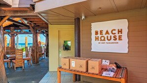 Una casa de playa con muebles de madera y un letrero que dice "BEACH HOUSE BY ROY YAMAGUCHI".