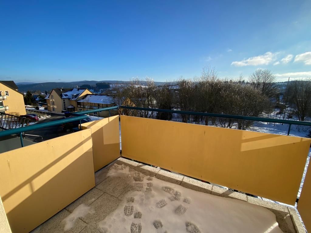 Un balcon donnant sur un paysage enneigé et des bâtiments.