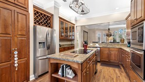 A spacious kitchen with wooden cabinets, stainless steel appliances, and a granite countertop. - Bonavita ~ Come make memories, 5BR/5BA beach home! (Gulf Shores)