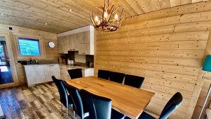 Una stanza con rivestimenti in legno, un tavolo da pranzo con sedie, un angolo cottura e un'ampia finestra.