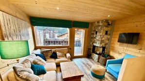 Un accogliente soggiorno con pavimento in legno, un divano, un tavolino da caffè e una TV a parete.