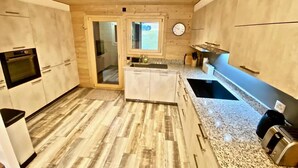 Una cucina moderna con pavimento in legno, mobili bianchi, piani di lavoro in granito e forno integrato.