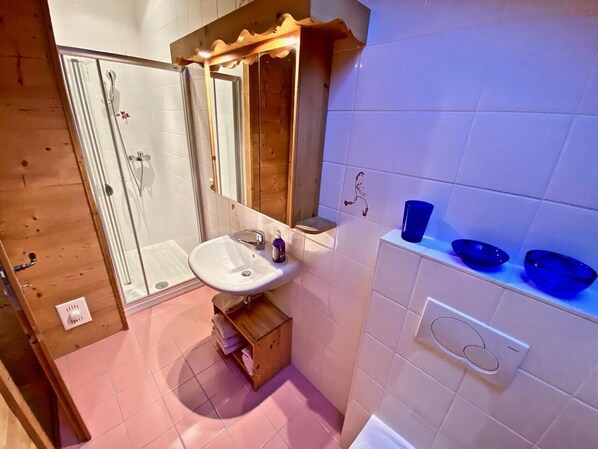 A bathroom with a shower, sink, and mirror.