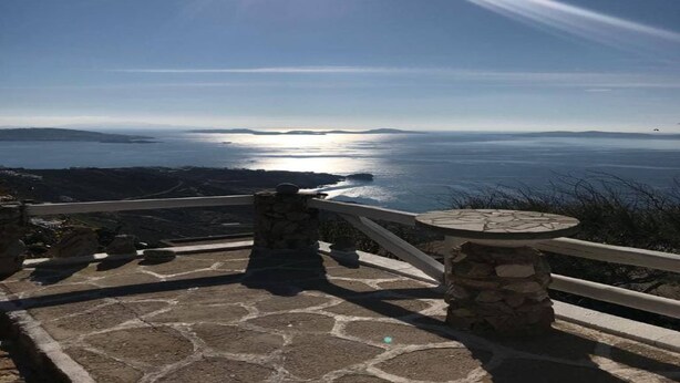 A stone pathway leading to a scenic overlook with a clear view of the sea and distant land. - Rare and magical panoramic view of Mykonos and the Aegean sea. (Mikonos)