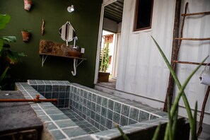 Une salle de bain avec un sol carrelé, un lavabo, un miroir et une échelle en bois.