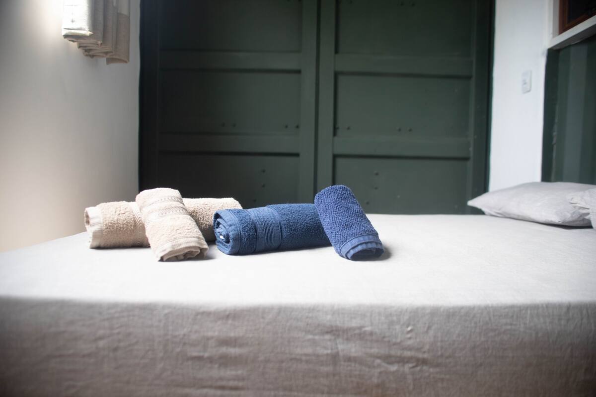 A bed with neatly folded towels in beige and blue colors.