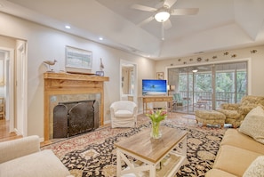 A living room with a fireplace, a television, and a large window. - Community pool, dock, river views! (Kiawah Island)