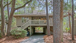 A two-story house with a covered walkway, surrounded by trees and a pathway. - Community pool, dock, river views! (Kiawah Island)