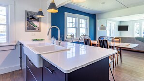 Une cuisine moderne dotée d’un îlot central, de luminaires suspendus et d’un coin repas avec des chaises et une table.