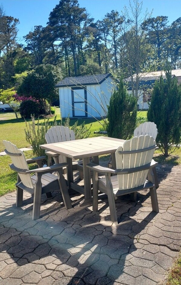Ein Holztisch mit vier Adirondack-Stühlen in einem Garten.