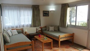 A cozy room with two wooden beds, a small table, and a radiator. - Haven of peace with garden and view - au Bouillat d'Anty (Châtel-Guyon)