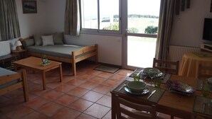A cozy room with a bed, a dining table set for two, and a TV. - Haven of peace with garden and view - au Bouillat d'Anty (Châtel-Guyon)