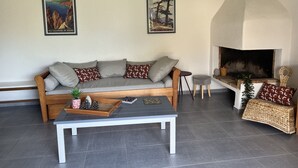 Een woonkamer met een bank, een salontafel, een open haard en twee ingelijste foto’s aan de muur.