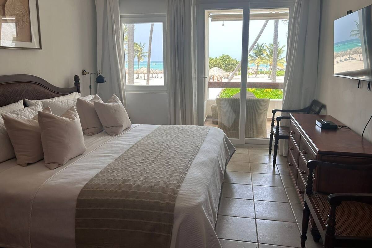 A bedroom with a bed, a desk, and a view of the beach.