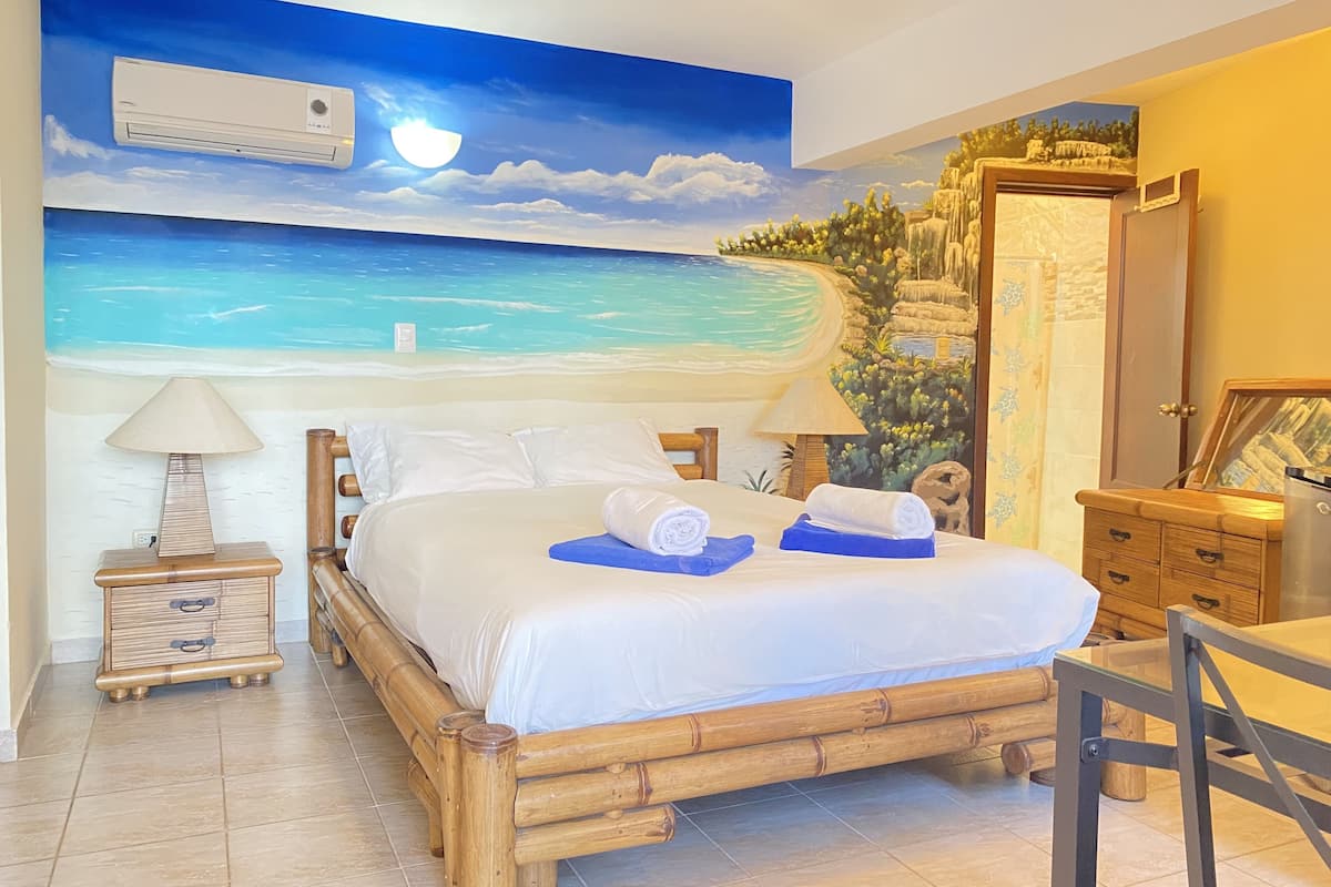 A room with a bed, a nightstand, a lamp, a chair, a desk, and a wardrobe.