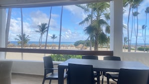 Una habitación con un gran ventanal con vista a la playa, amoblada con una mesa y sillas.