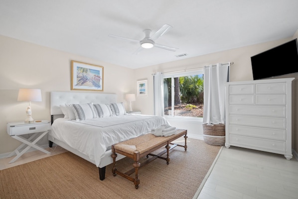 A bedroom with a bed, bedside tables, a bench, a dresser, and a ceiling fan.