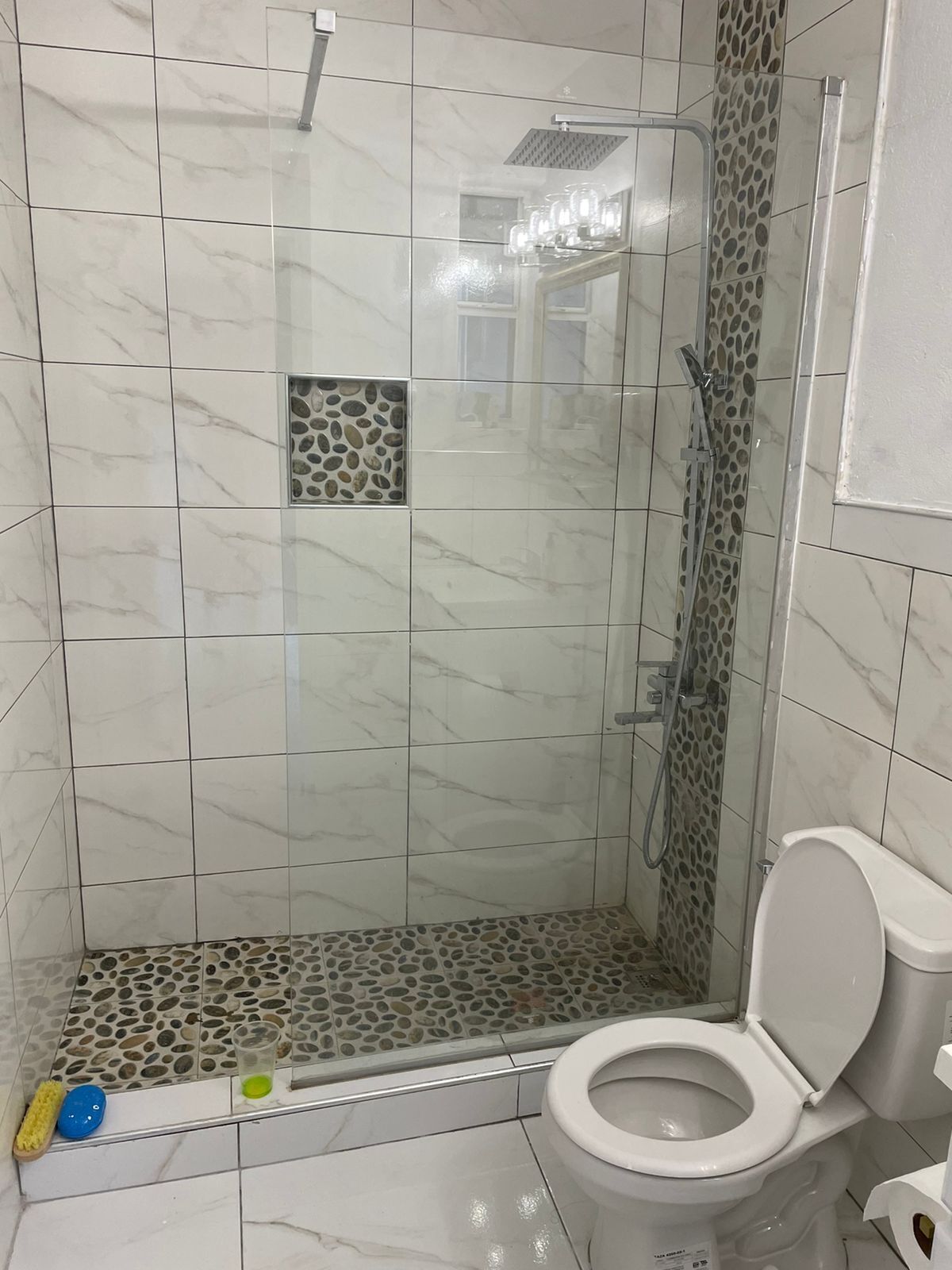 Une salle de bain avec une douche, des toilettes et une petite fenêtre.
