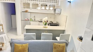 A compact living space with a kitchenette, a sofa with cushions, and a small dining area.