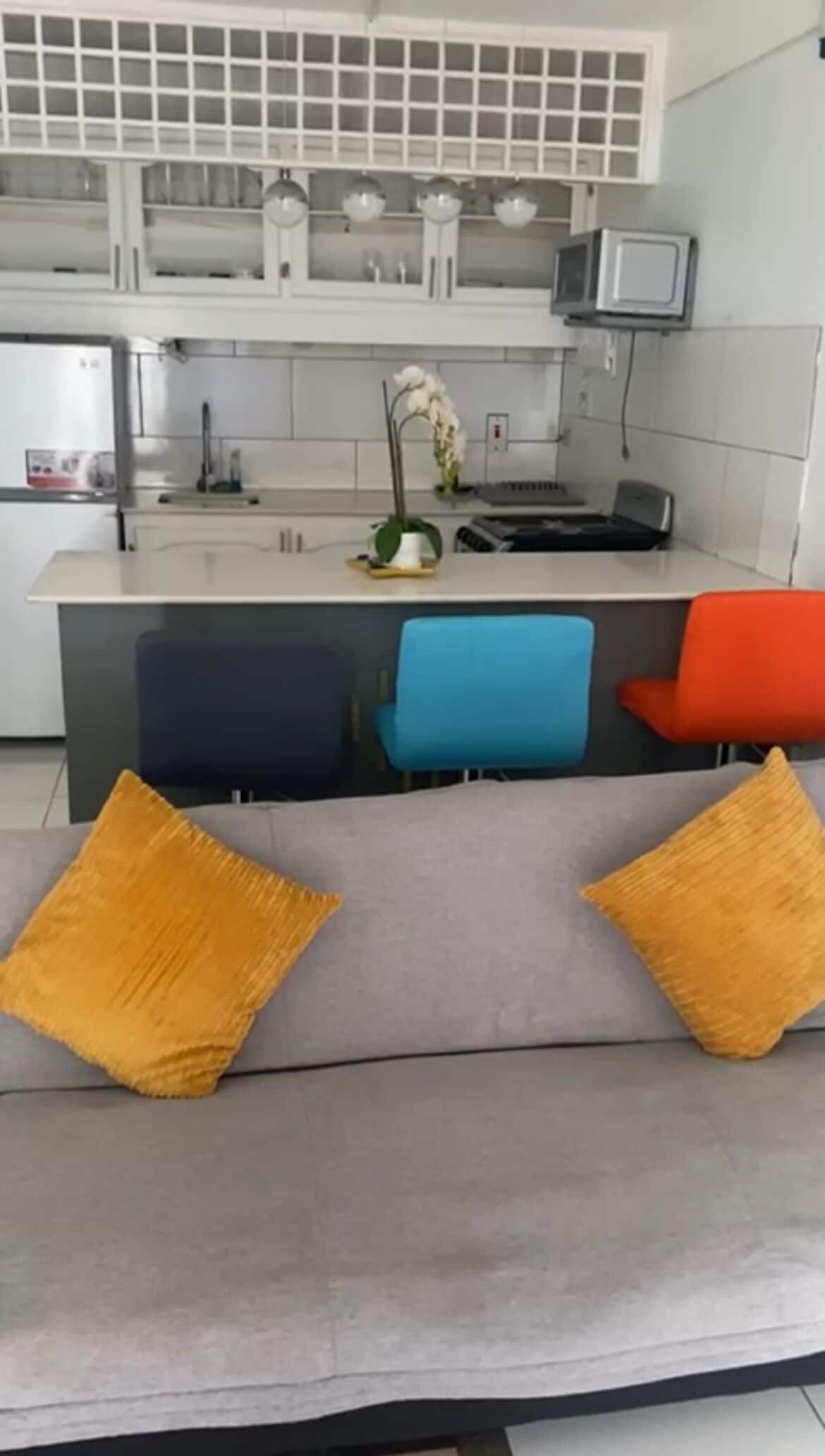 A modern kitchen with white cabinets, a central island, and a blue chair.