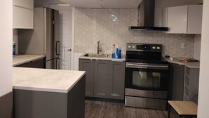 A modern kitchen with stainless steel appliances, a hexagonal tile backsplash, and grey cabinetry.