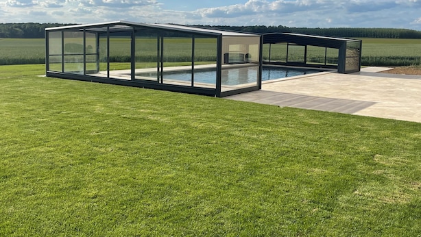 Un espace piscine extérieur moderne, doté de parois vitrées et offrant une vue dégagée sur le paysage environnant.